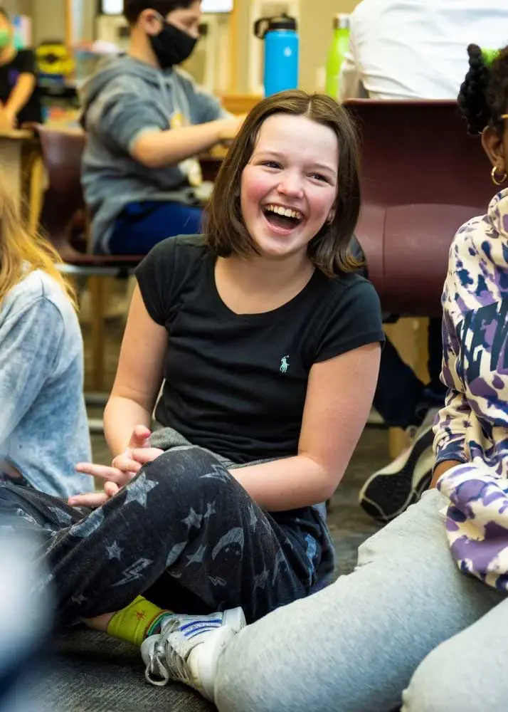 Student kneeling on the ground happily smiling